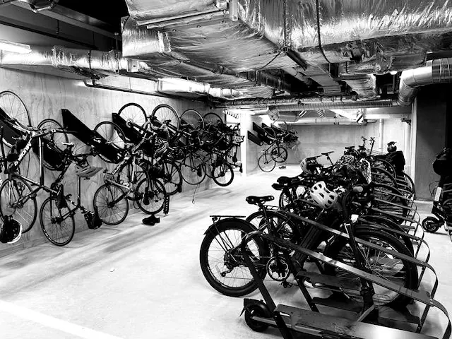 Basement end-of-trip bike room with wall racks above floor racks holding bikes and e-bikes